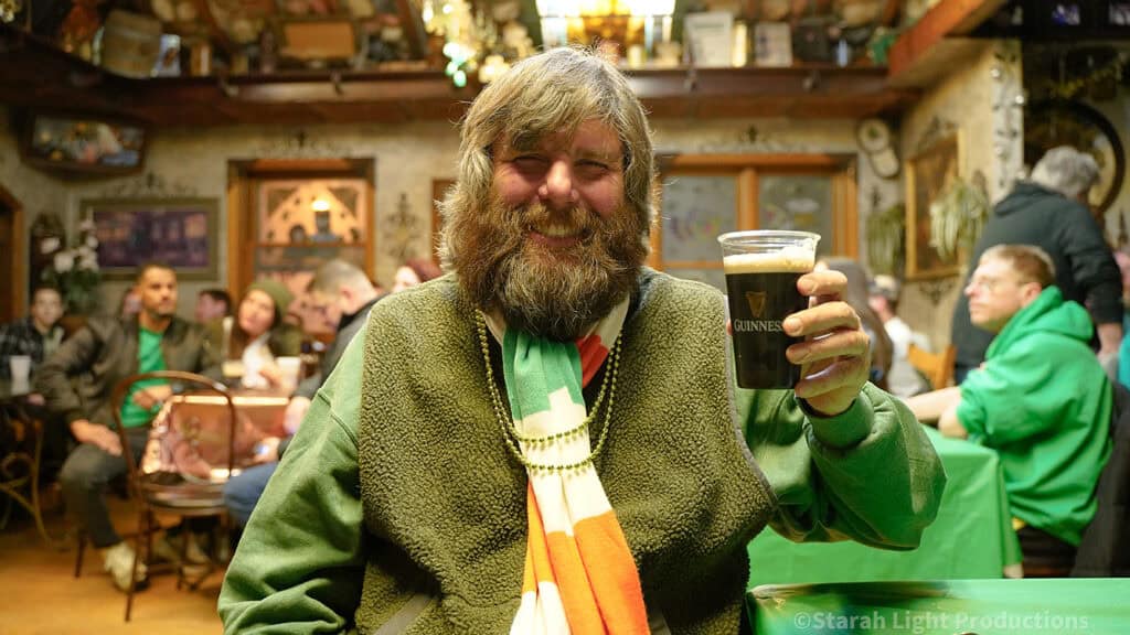 man holding Guinness and smiling in pub