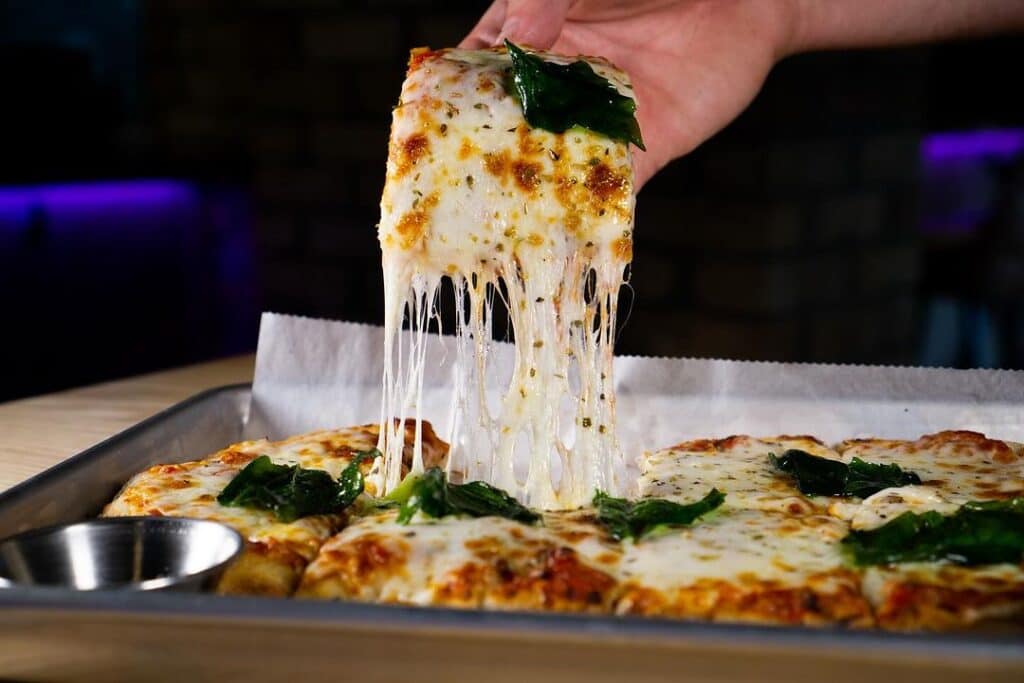 picking up slice of cheesy pizza