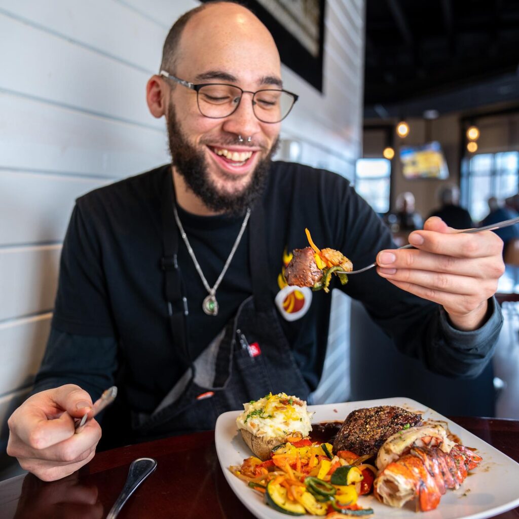 man eating surf and turf smiling