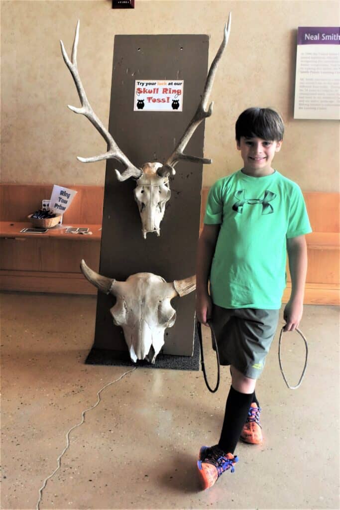 boy standing in front of skull ring toss game